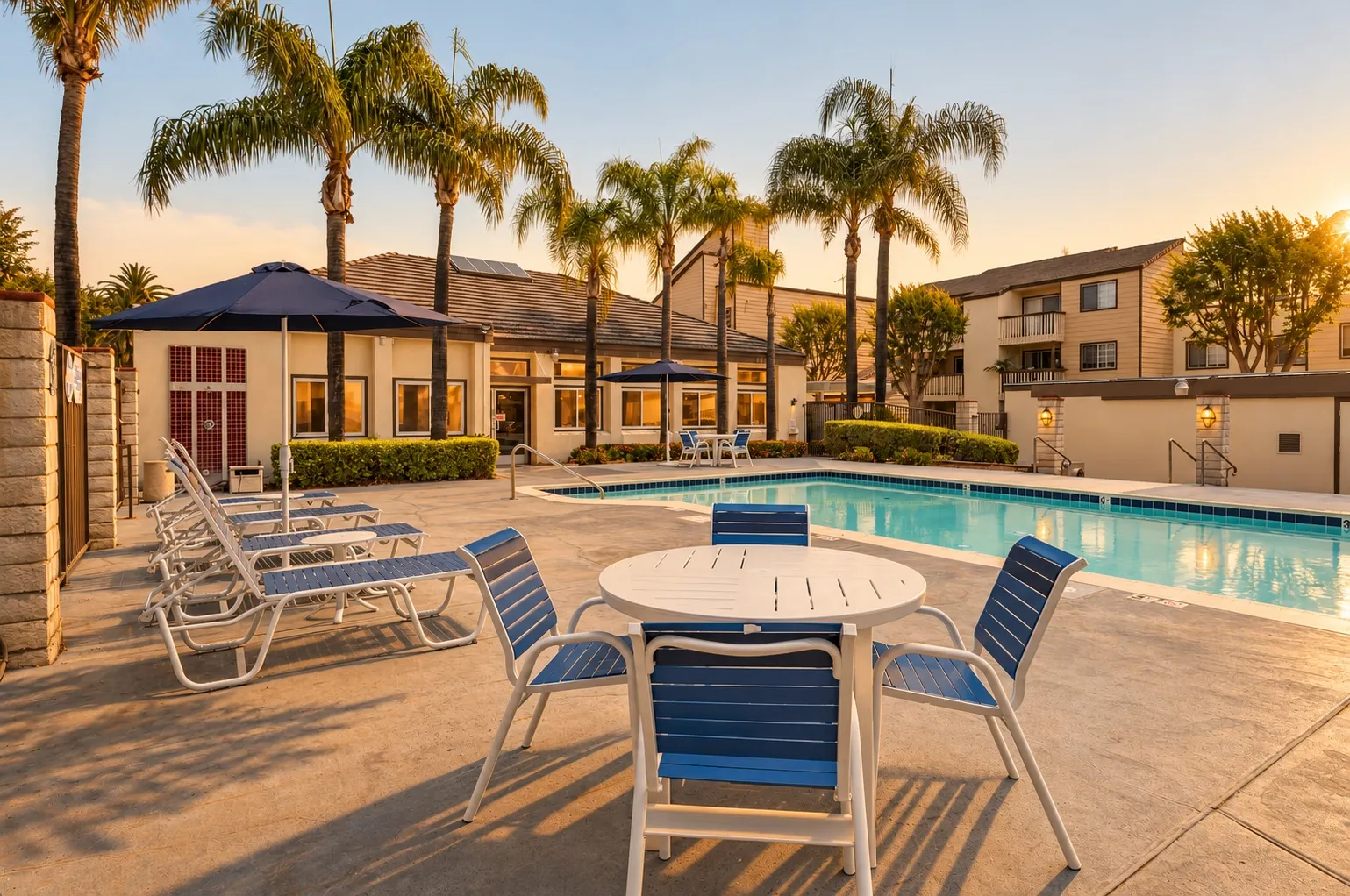 Pool deck with lounge chairs and a patio table at sunset